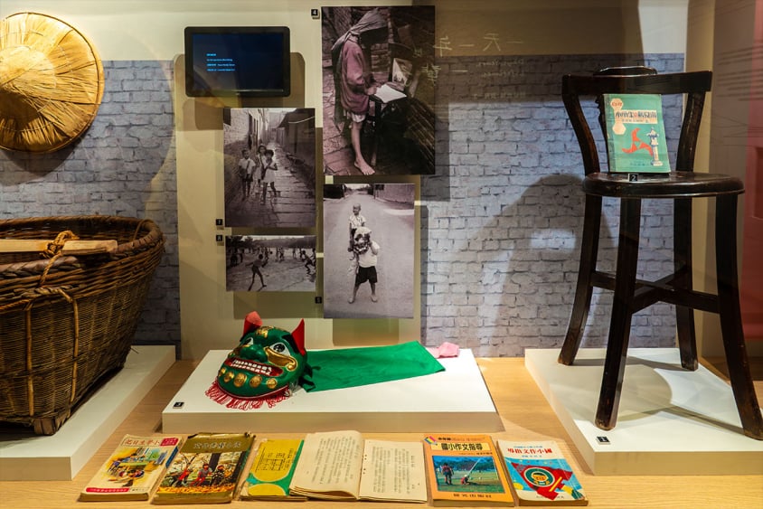 展區文物陳列照片：展示傳統竹編籃、童玩獅頭、復古書籍與舊式木椅。