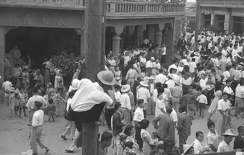 1959年媽祖一千週年祭，中山路與民族路口人潮洶湧，一名男子爬上電線桿拍攝記錄。