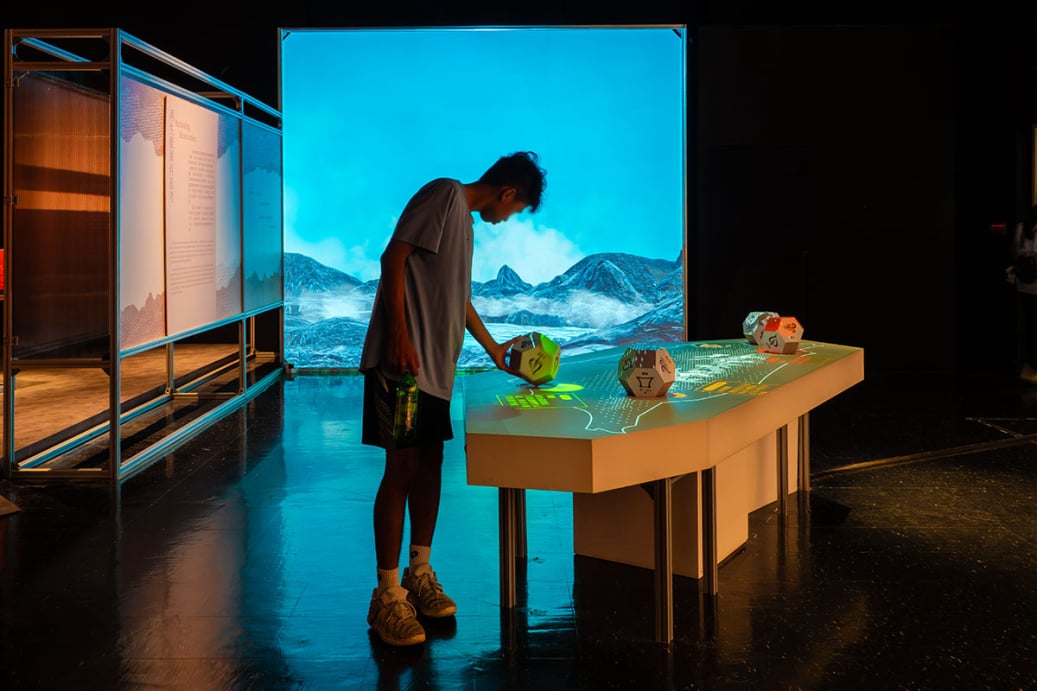和熱共榮特展「永續同行」展區，民眾於投影桌前操作幾何骰子互動裝置